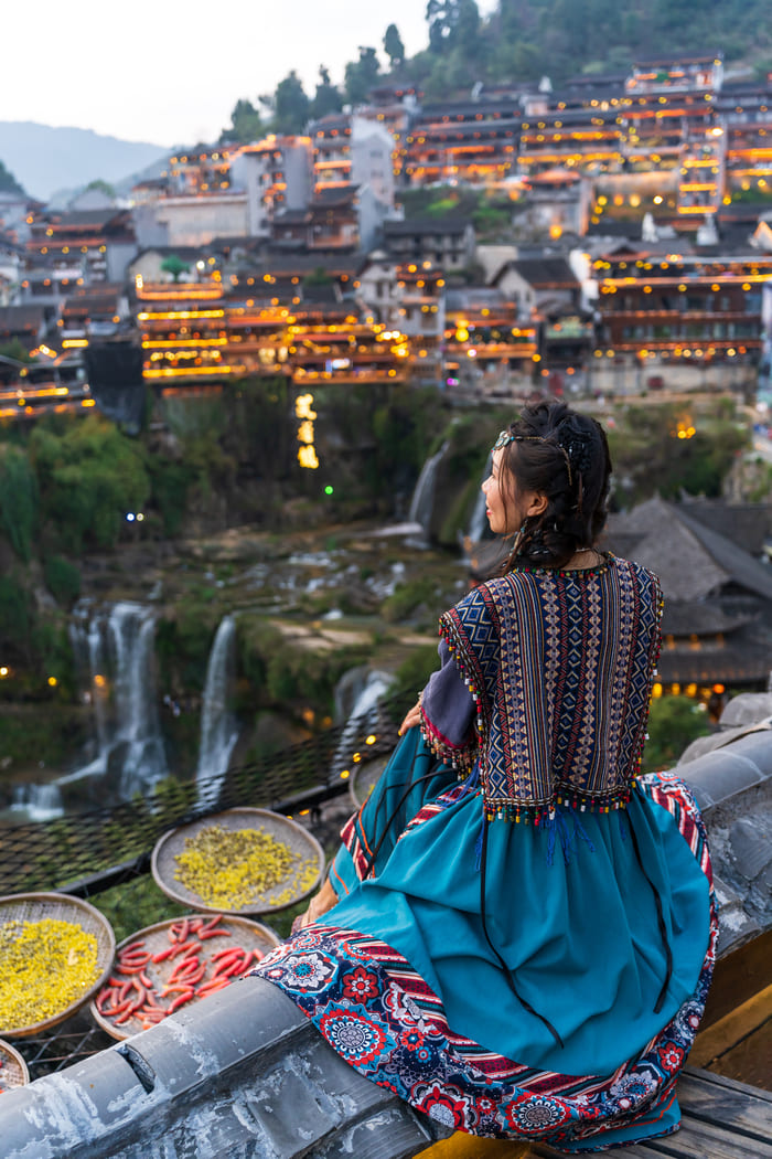 una mujer sentada viendo la vista de la ciudad de lijiang china