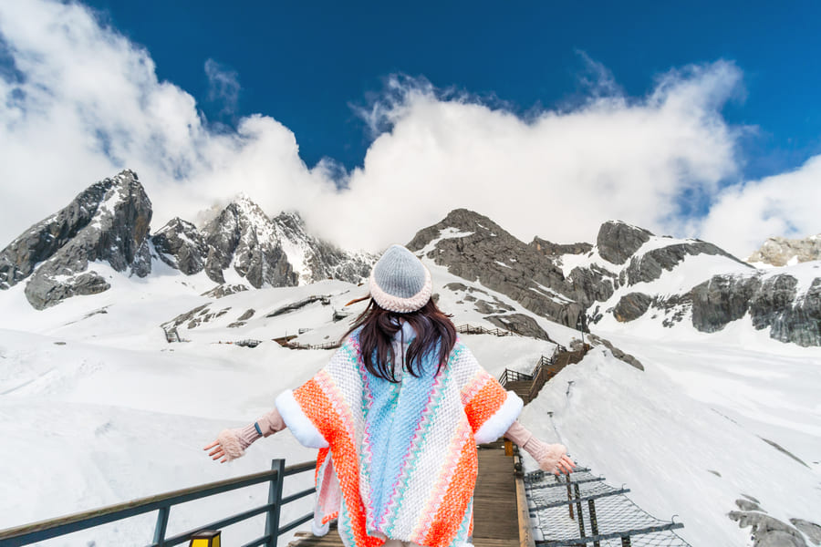 Chica en medio de una caminata en Yulongshang, con montañas nevadas de fondo
