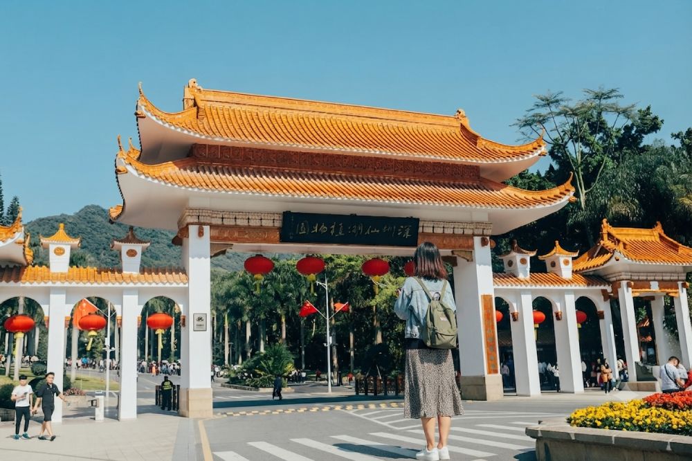 Foto de turista en puerta de una templo chino con fondo de cielo azul
